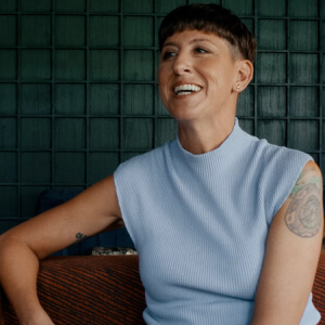 Woman smiling on a green wall background.