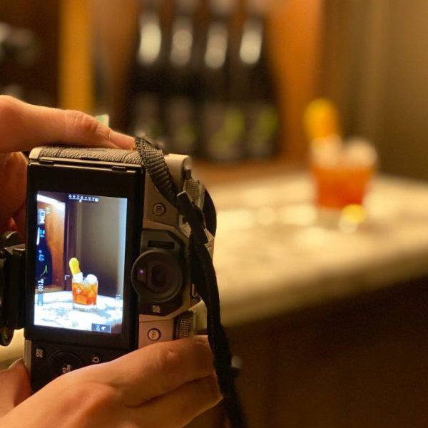 person holding a camera and taking a picture of a drink
