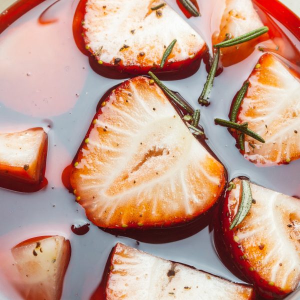 Firefly macro shot of strawberries and rosemary chopped up and in a red in liquid liqueur sho 857126