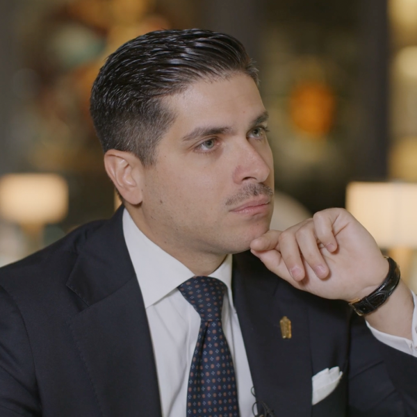 A man in a suit and tie with his hand on his chin.