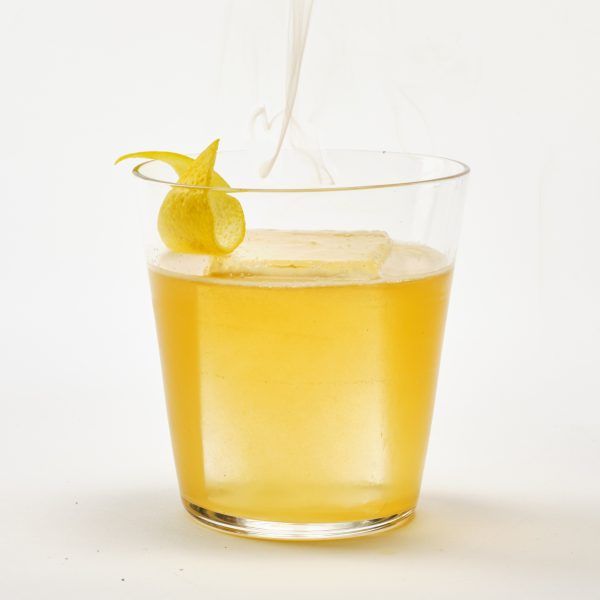 An Longbranch cocktail, on the rocks, against a white background with a whisp of smoke.