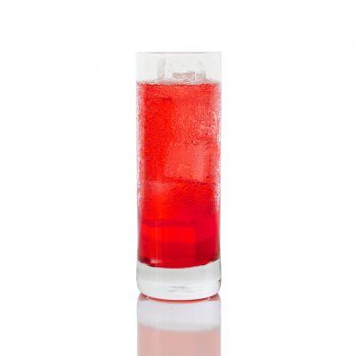 A Campari Soda in a sweating highball glass, sits on a white backdrop.