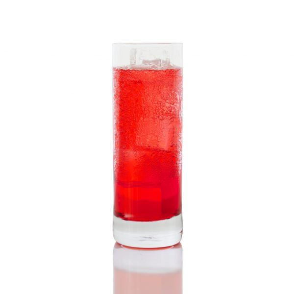 A Campari Soda in a sweating highball glass, sits on a white backdrop.