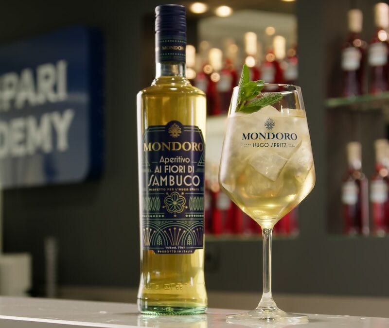 Copa de Mondoro Hugo Spritz, junto a una botella de Mondoro